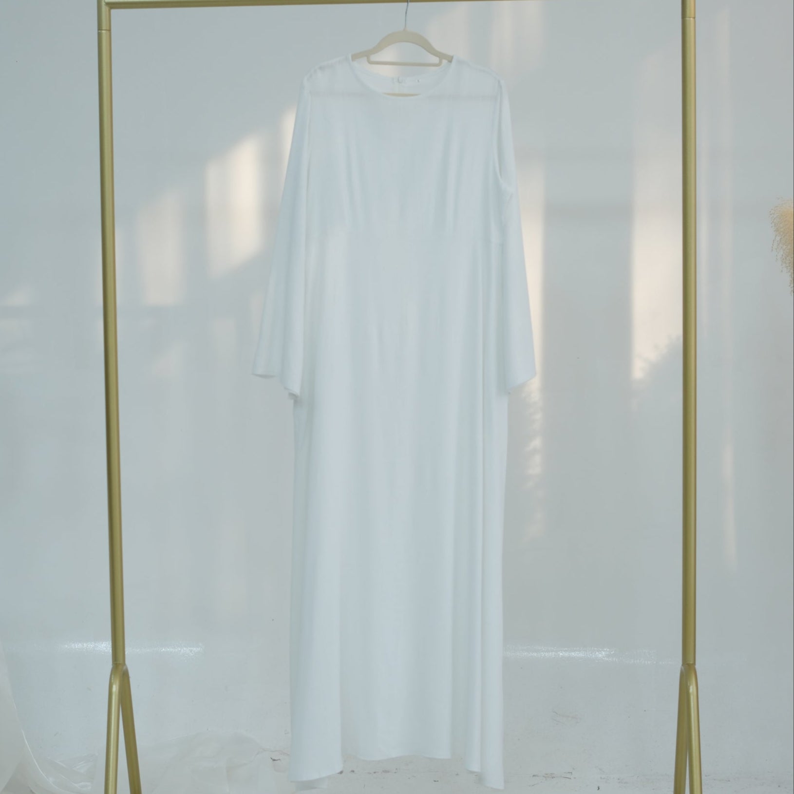 Gold clothing rack with a white shirt on a white background